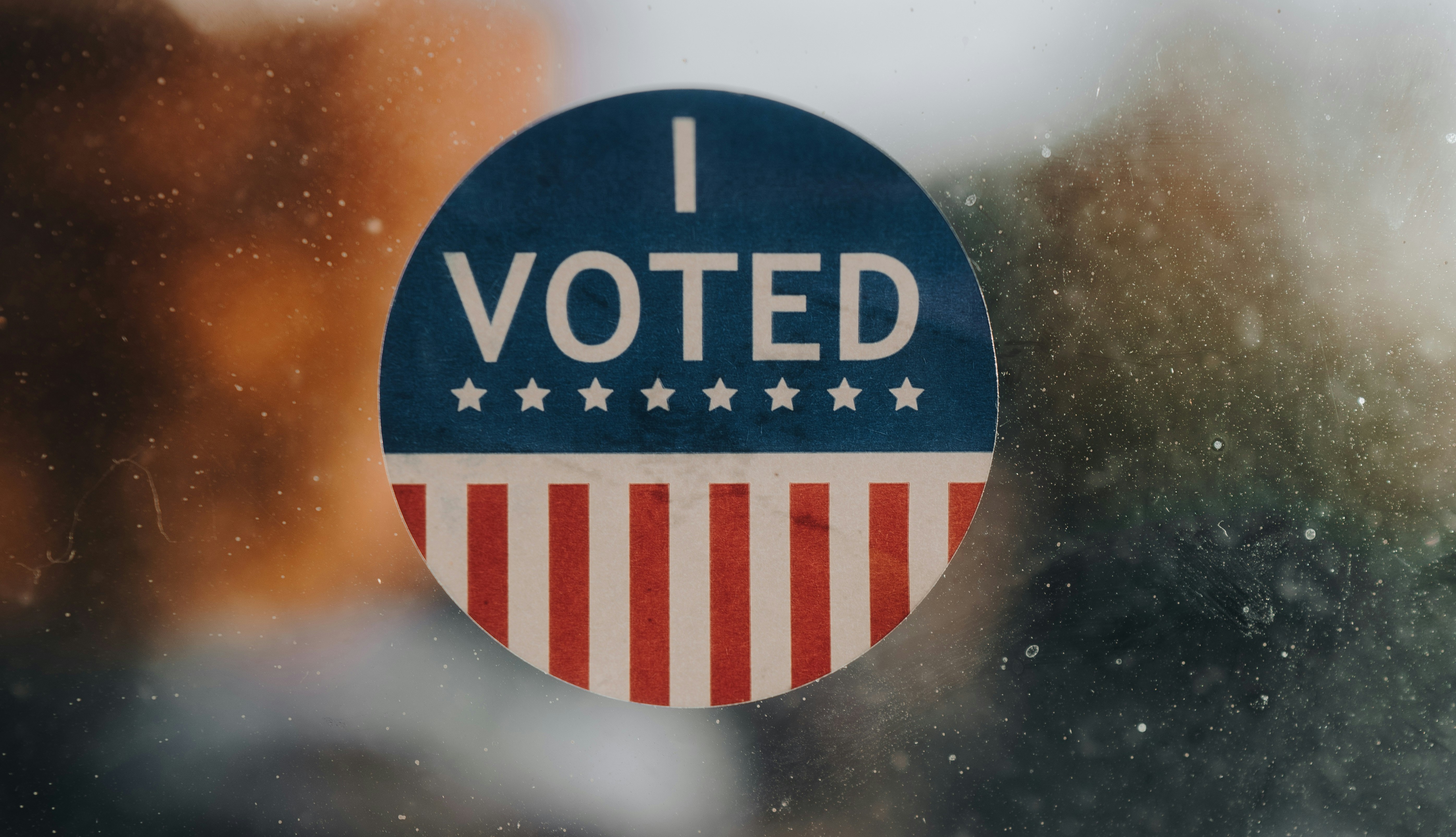 I Voted sticker on an American flag background